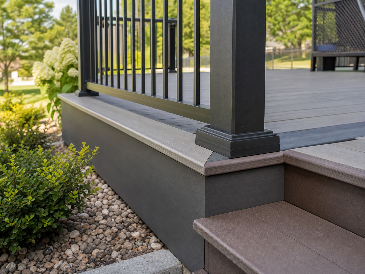 Close detail of composite deck railings, post base, stair tread, and landscaping