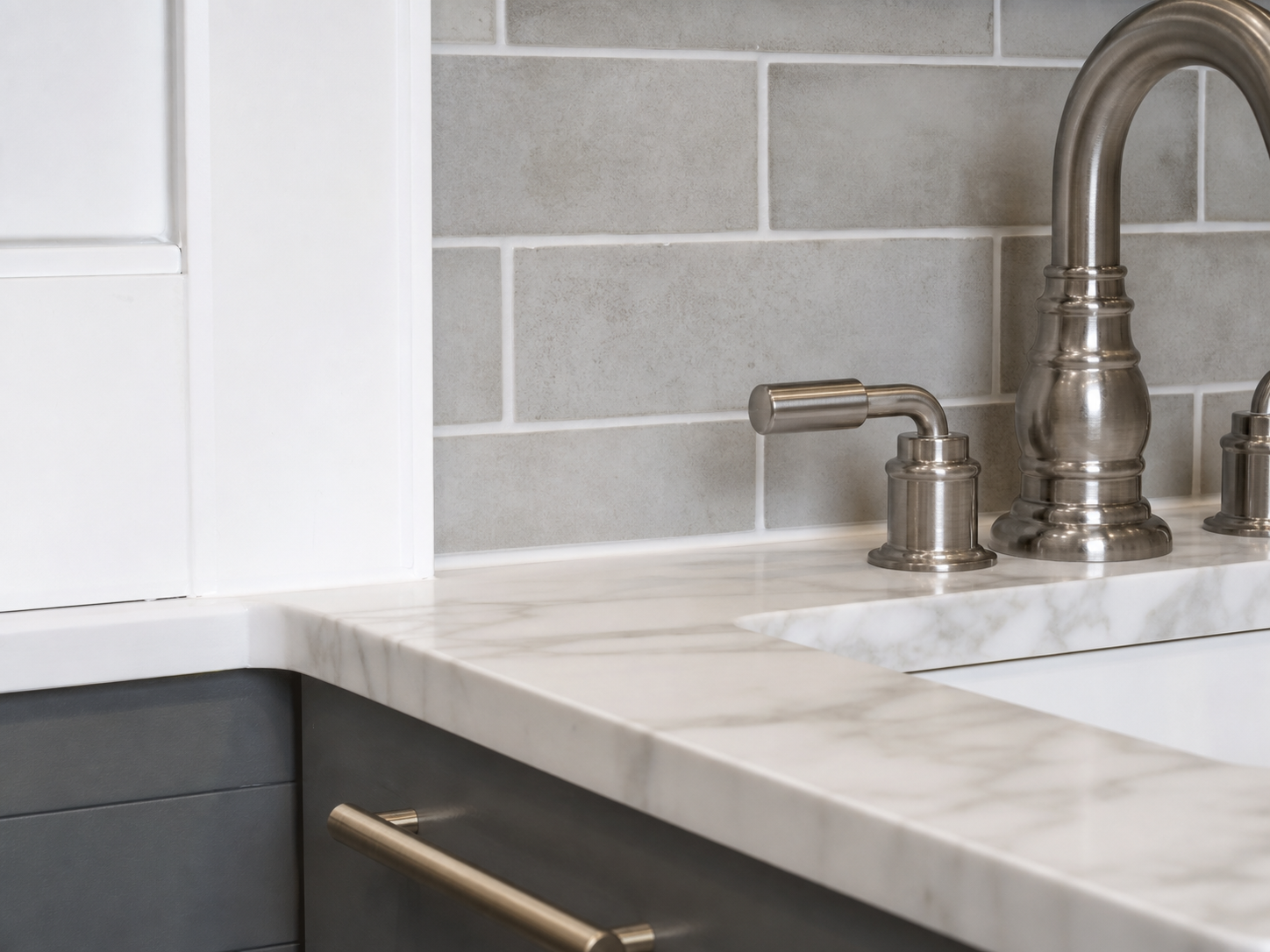 Close detail of tile, stone countertop, faucet, and cabinet finish in a remodel