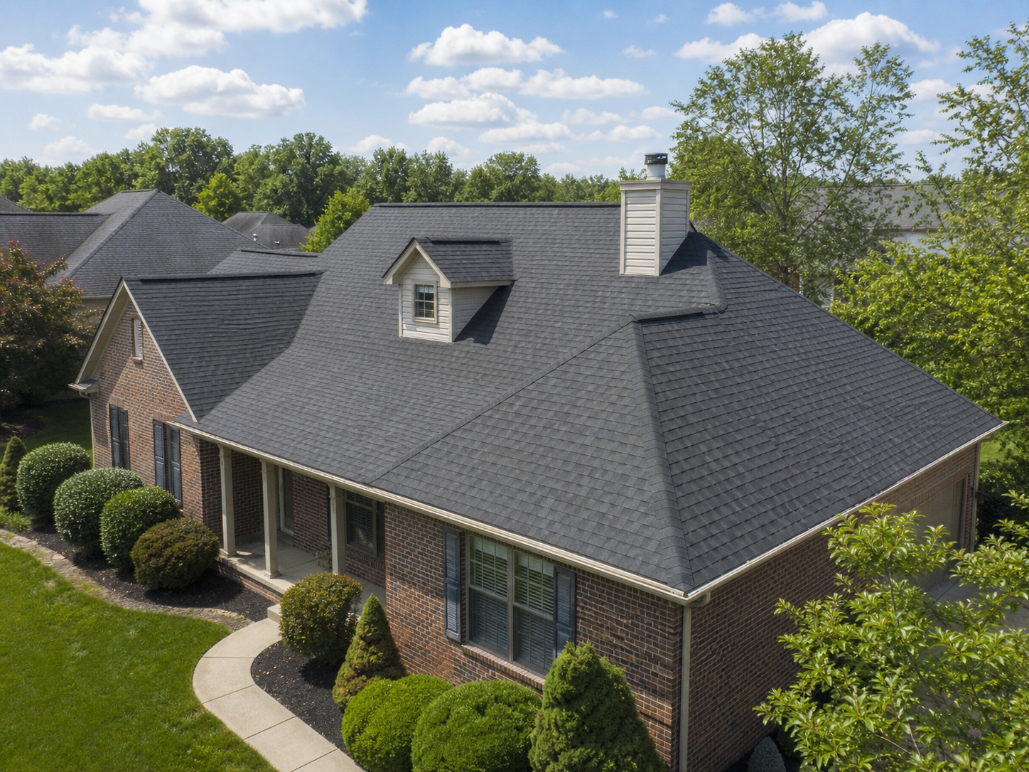 Finished asphalt shingle roof with ridge vent and clean roof planes on a brick home
