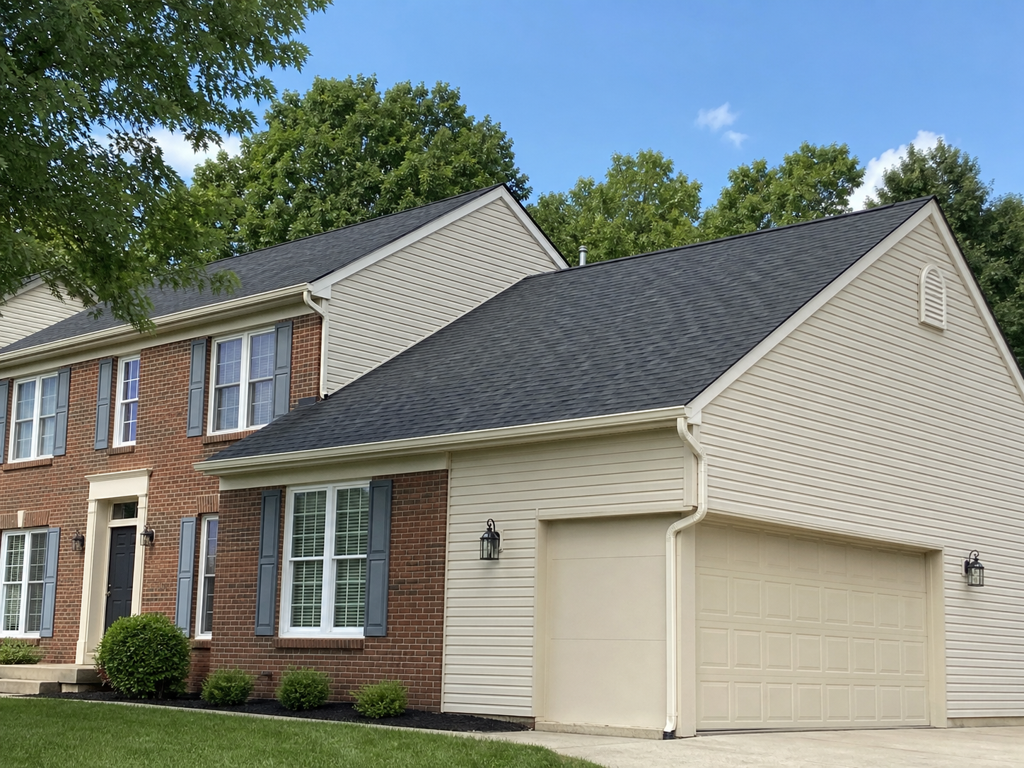 Completed asphalt shingle roof on a clean suburban brick and siding home